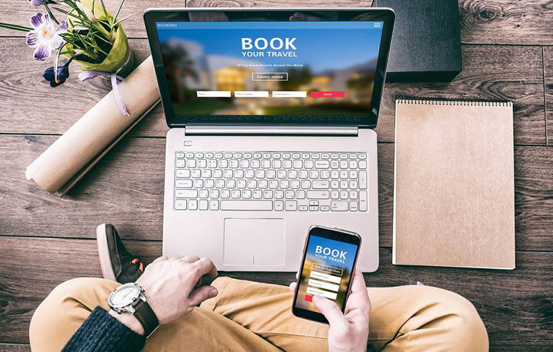 Man using a laptop and smartphone for booking hotel online